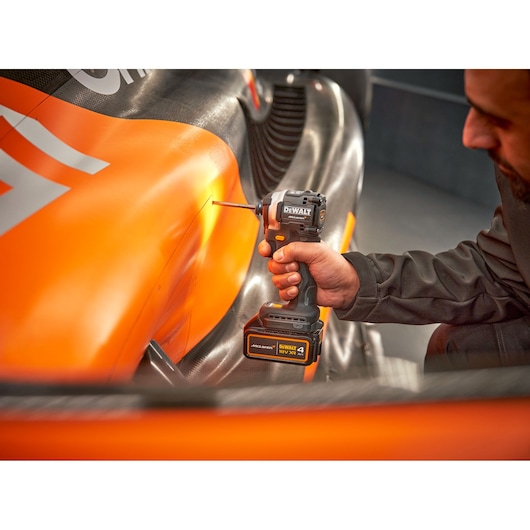 McLaren mechanic using DEWALT/McLaren impact driver on McLaren racing car
