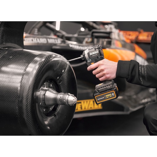 McLaren mechanic using DEWALT/McLaren impact driver on McLaren racing car