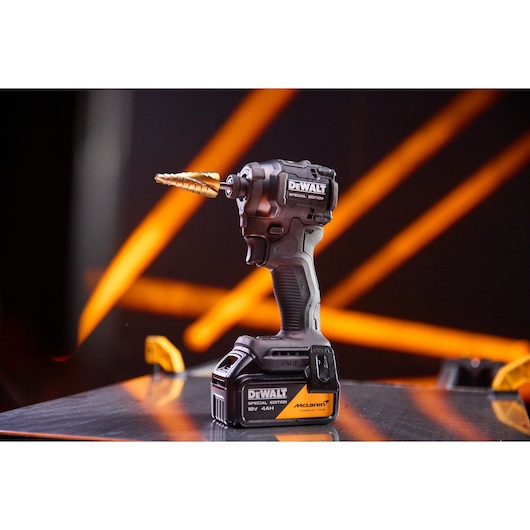 DEWALT x McLaren F1 Team 18V XR Special Edition Impact Driver with 4Ah battery standing on a metal sheet