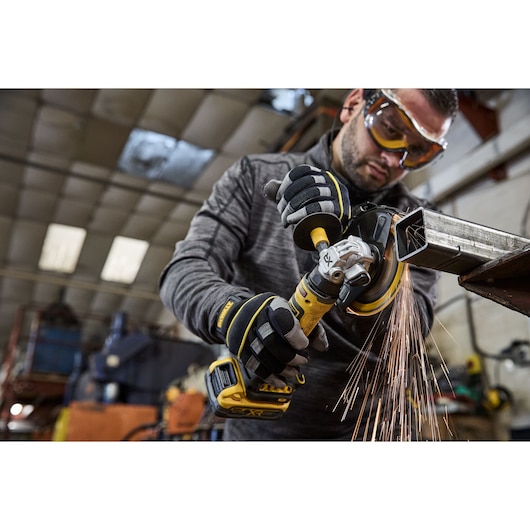 Worker uses the DEWALT 18V XR Compact 125mm Angle Grinder with 3.5ah battery to cut steel square tubing