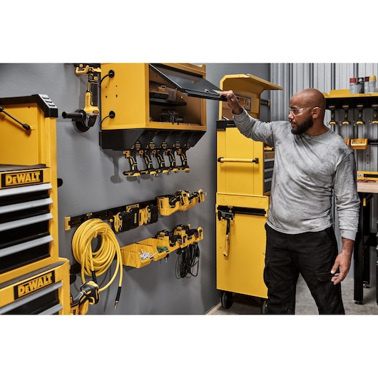 A Person Opening a DEWALT Wall Cabinet Featuring Batteries and a DEWALT Chest and Cabinet